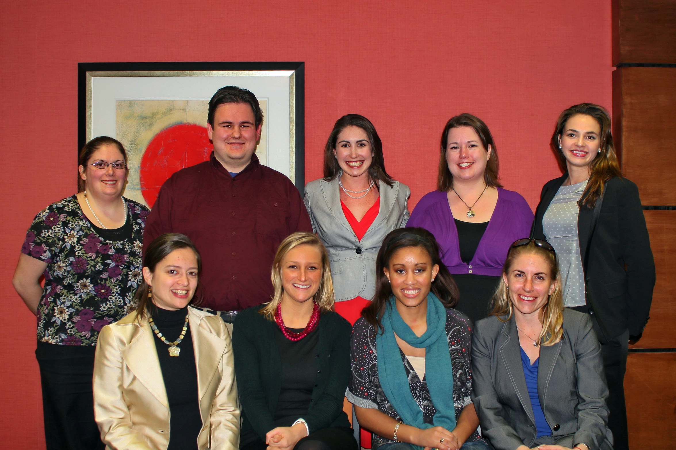 a group of young women and men pose in front of a portrait of themselves