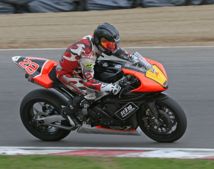 the motorcyclist in the orange helmet is racing his bike