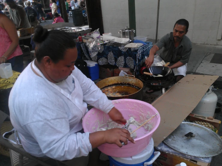 man peeling paper in bucket in outdoor market stall