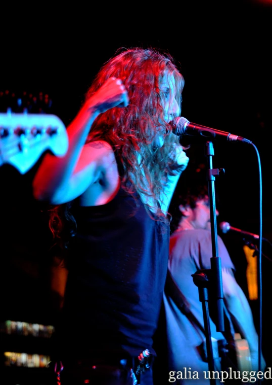 a male singer with long hair in front of microphone