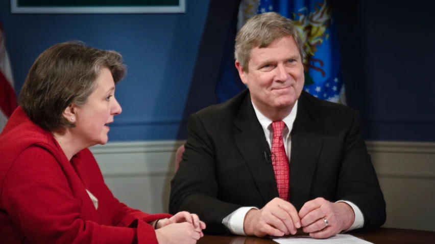 a woman sitting at a desk with an office man