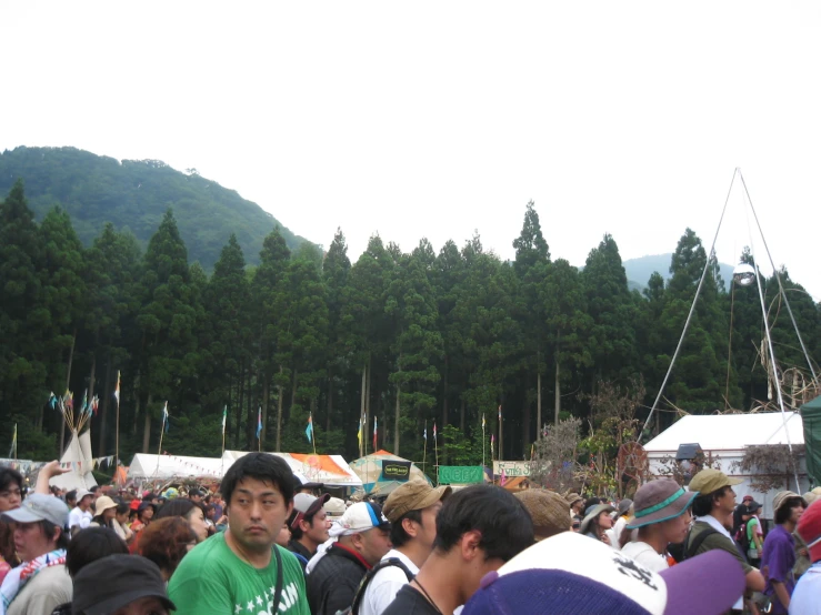 a crowd of people standing around near tall trees