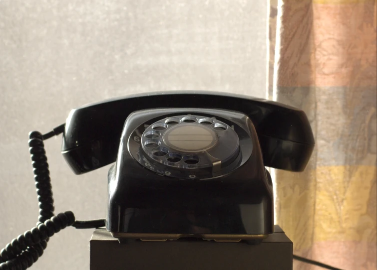 an old style telephone sitting on top of a block of wood