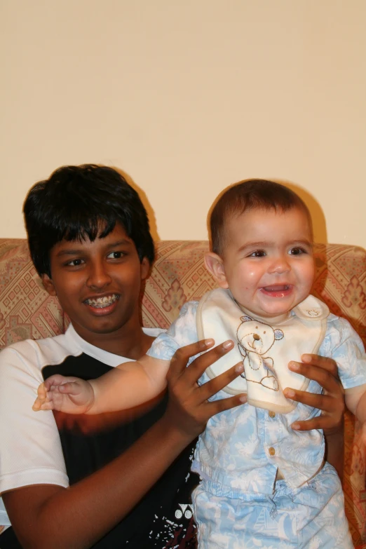 a baby sits on someone's lap and holds his hand