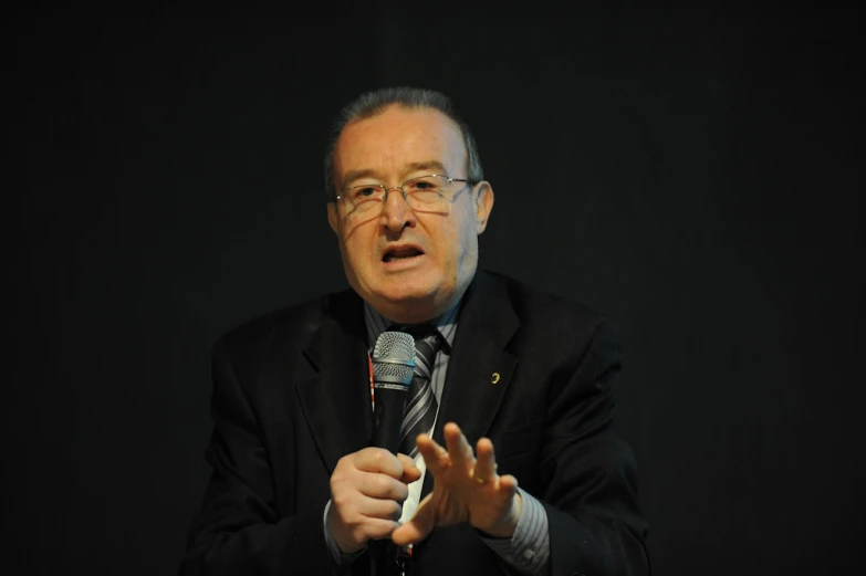 a man in a suit and tie standing in front of a microphone