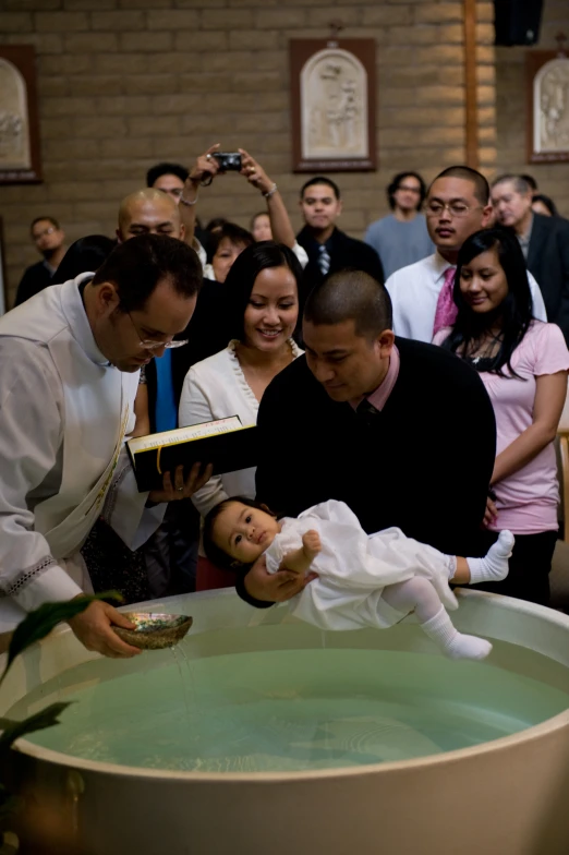 a small child being fed water by a man