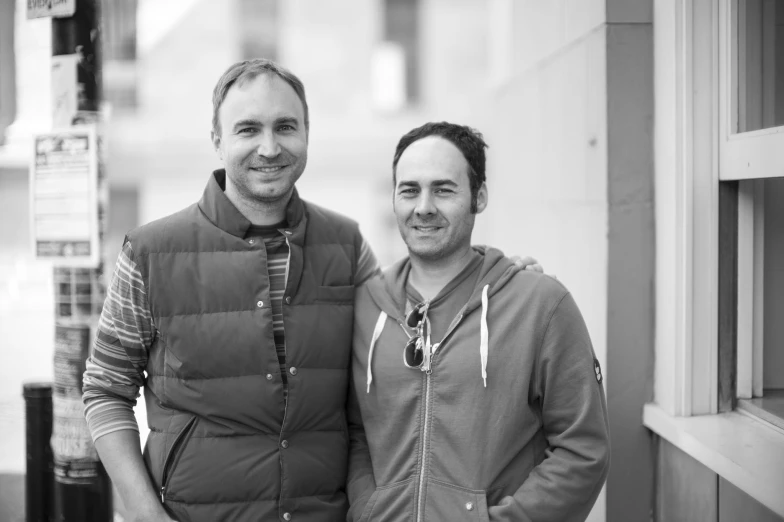 black and white po of two men standing in front of a city building