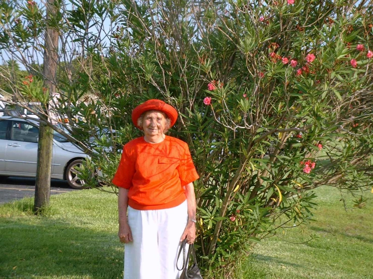 a woman wearing an orange and white outfit posing next to a tree