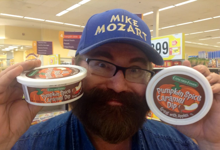 a man holding two containers of pumpkin flavor ice cream in the store