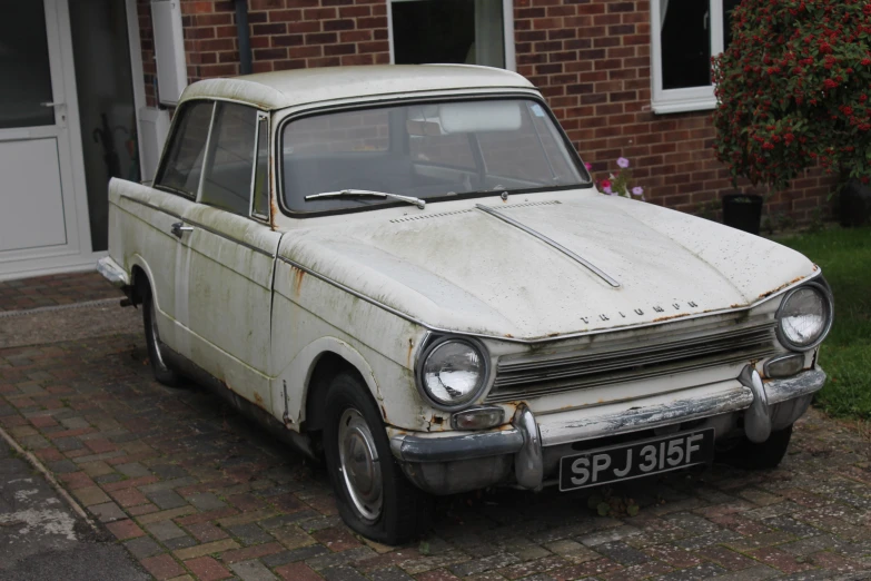 a small old car that is white and rusting