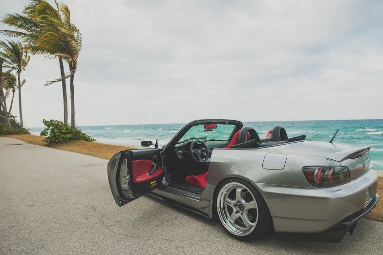 a grey sports car with a red seat on the beach