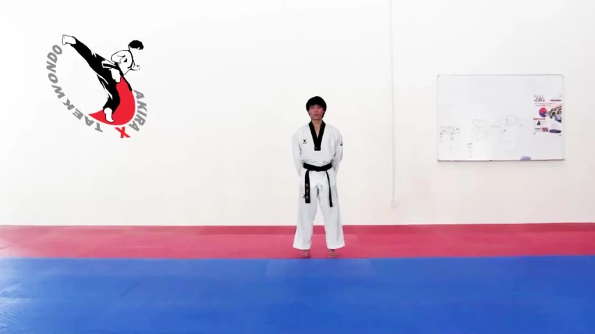 a person in a white suit and black belt standing in front of a wall