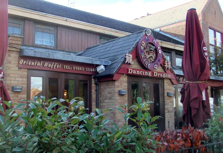 a restaurant outside with a red awning and bushes