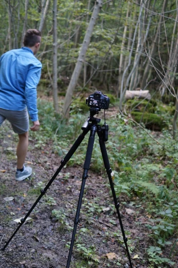 man walking away from camera tripod in the woods
