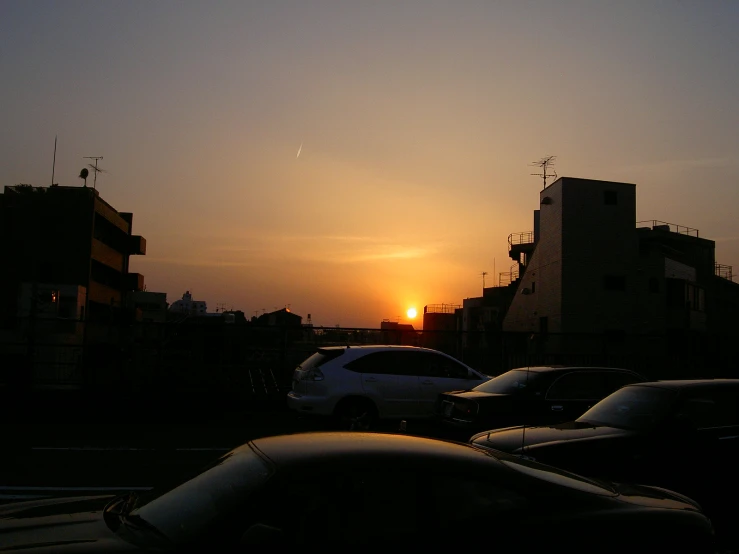 a sunset view of some cars on the side of a street