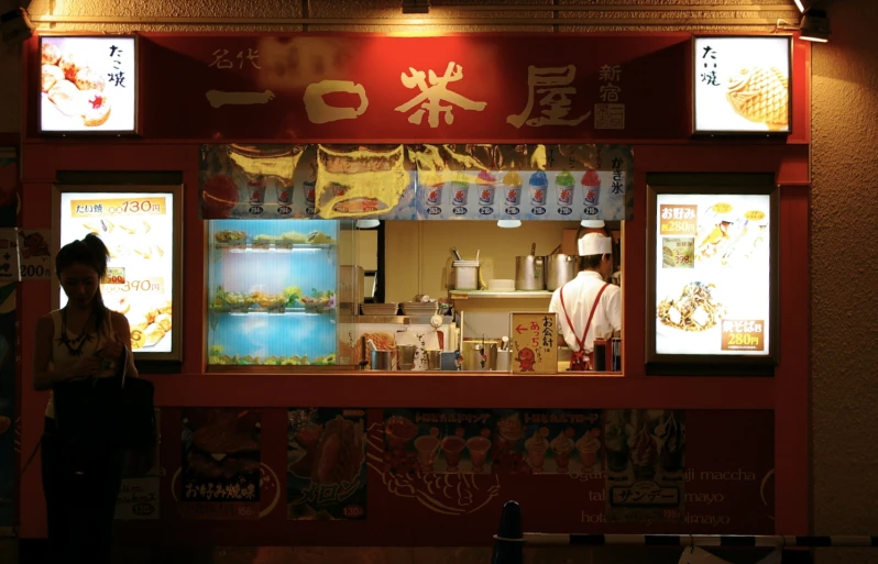 a food stand displaying different kinds of foods and people standing outside the shop