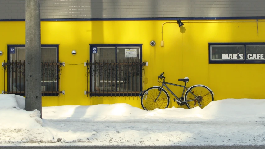 a bicycle sits parked in front of a bright yellow building