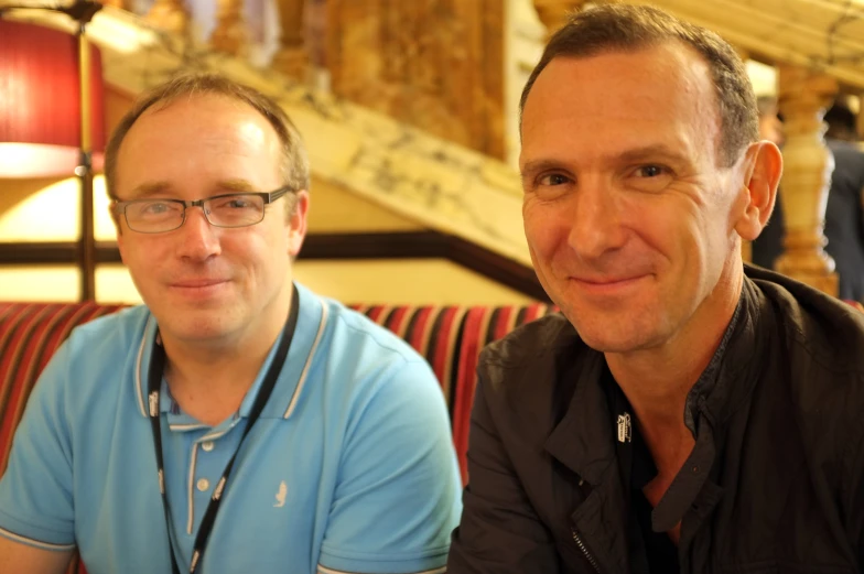 a man smiling while standing next to another man