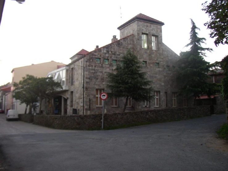 a long stone building on the corner of a street