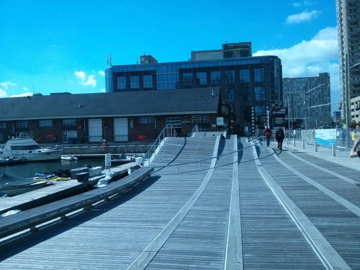 people are walking along the bridge and some boats