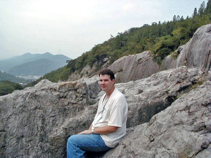 a man sitting on a big rock in a mountain