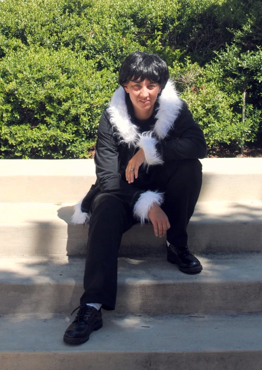 a man wearing fur and fur collar sitting on steps