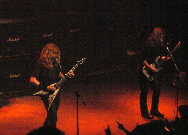 two guitar players on stage while others watch