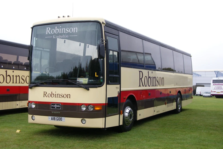 two large buses parked next to each other on a field