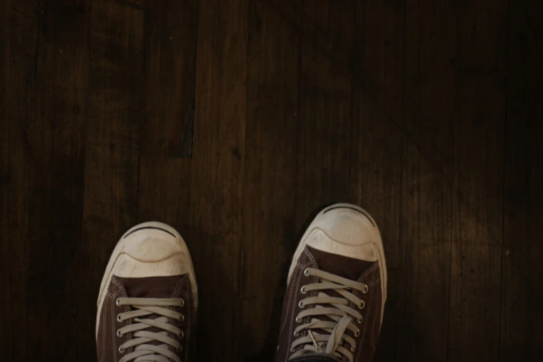 a pair of white and brown shoes on a dark wood floor