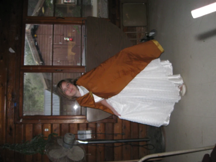 a woman in white and brown dress holding up a shawl