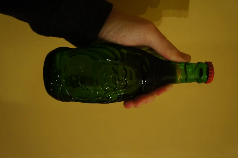a hand holding a bottle of green beer