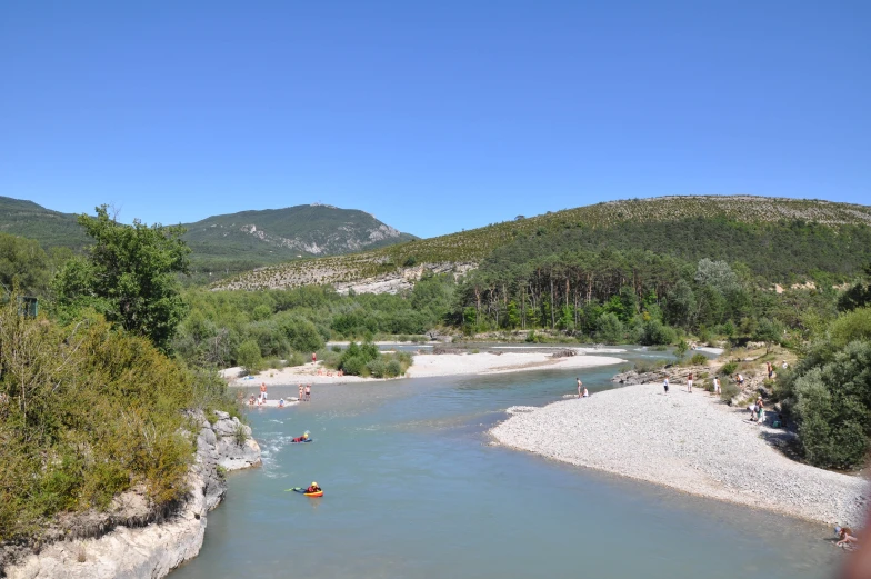 people in rafts down a river with green hills in the background