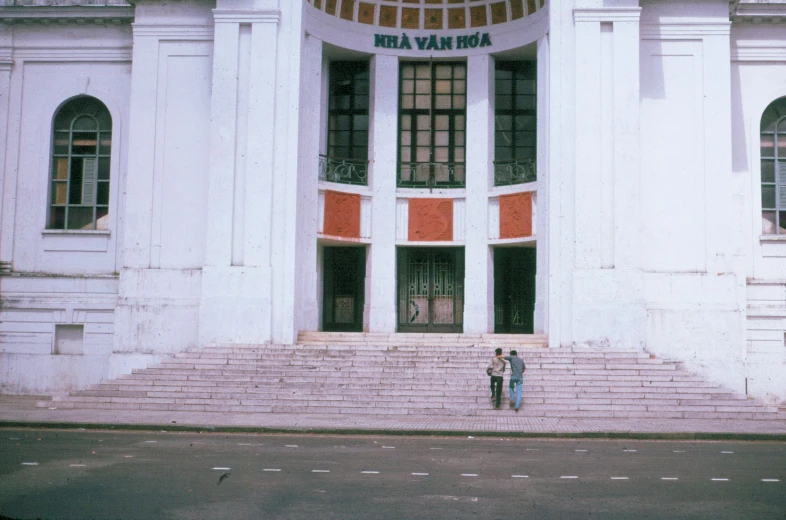 a couple is hugging in front of a large white building