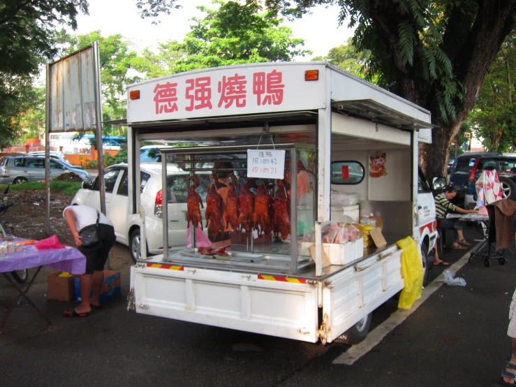 a group of people stand behind a truck with meat