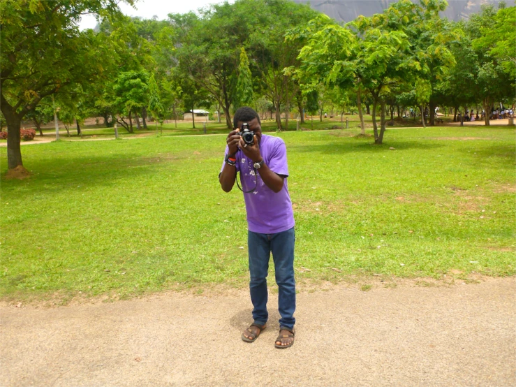 man taking picture of himself on his camera in a park
