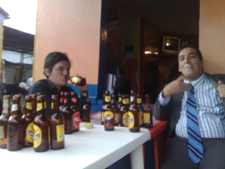 two people sitting at a table with bottles