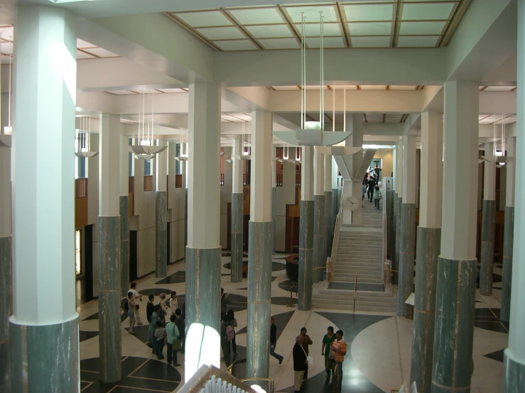 several people walking down the walkway in a building