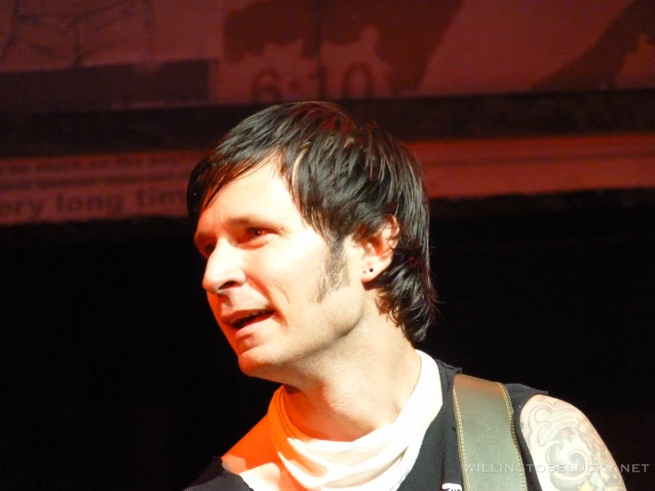 a man playing guitar wearing an orange band aids