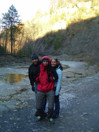 three people in front of a stream in the mountains