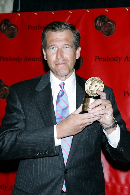 a man in a suit holds up a golden award