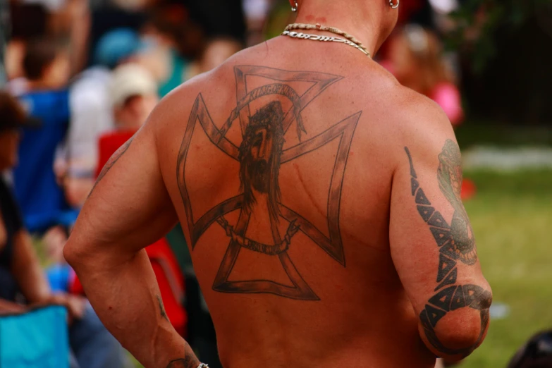 a man with some tattoos standing in a field