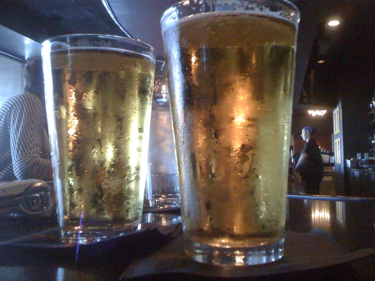 two glasses of beer on a bar counter