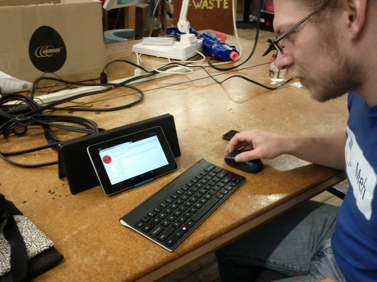 a young man sits at a table using his electronic device