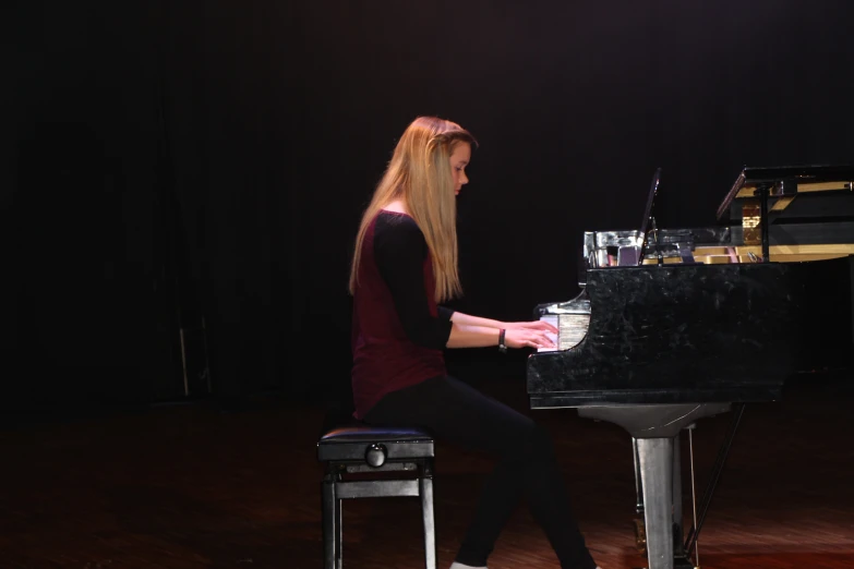 a woman sits at the piano while holding onto her hand