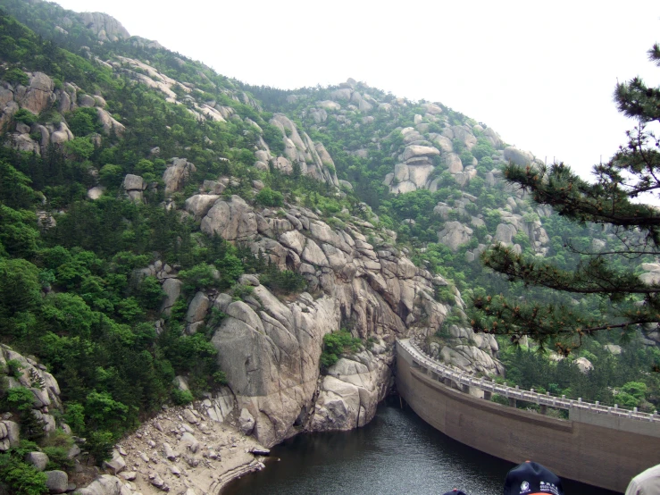 a bridge on the side of a mountain, leading to a body of water