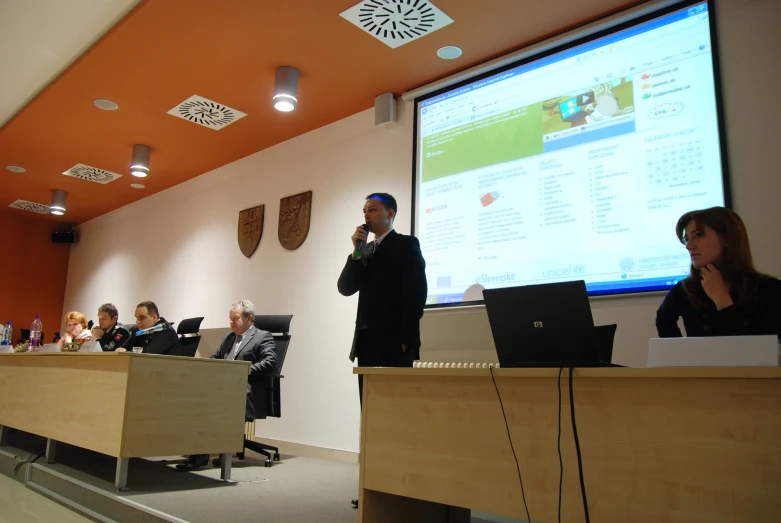 several people at the front of a room listening to a speaker