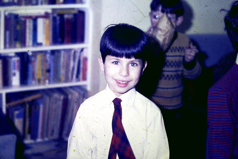 boy wearing shirt and tie in room full of books