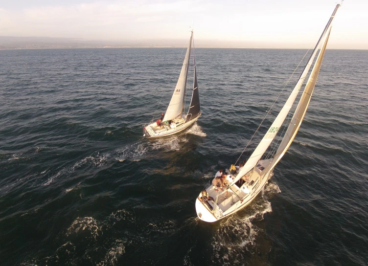 a pair of sail boats sailing side by side on open water