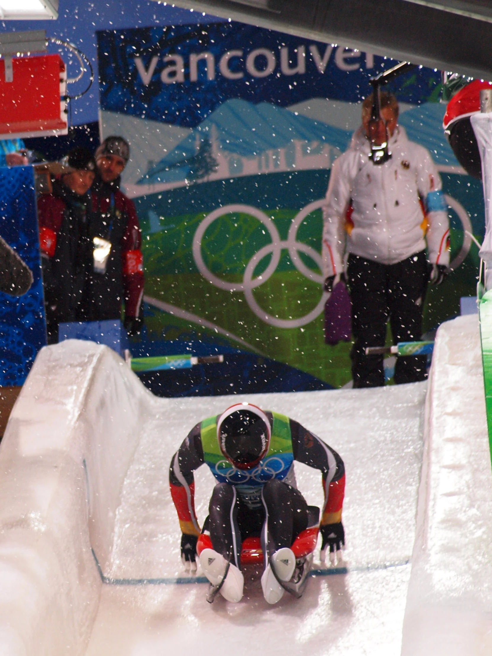 two snow skiers riding down a small hill