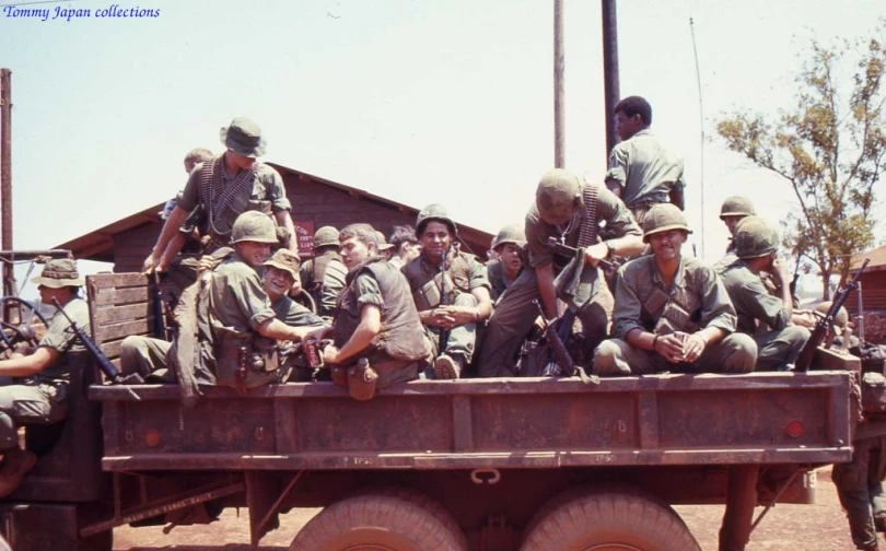 men in the back of a pick up truck with soldiers